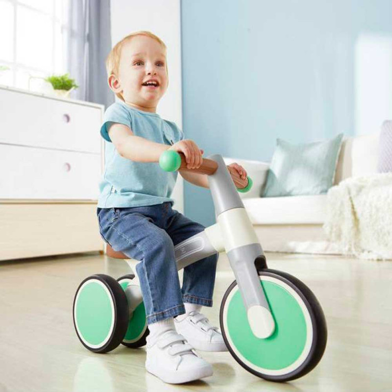 Enfant avec son premier tricycle vert pastel de Hape