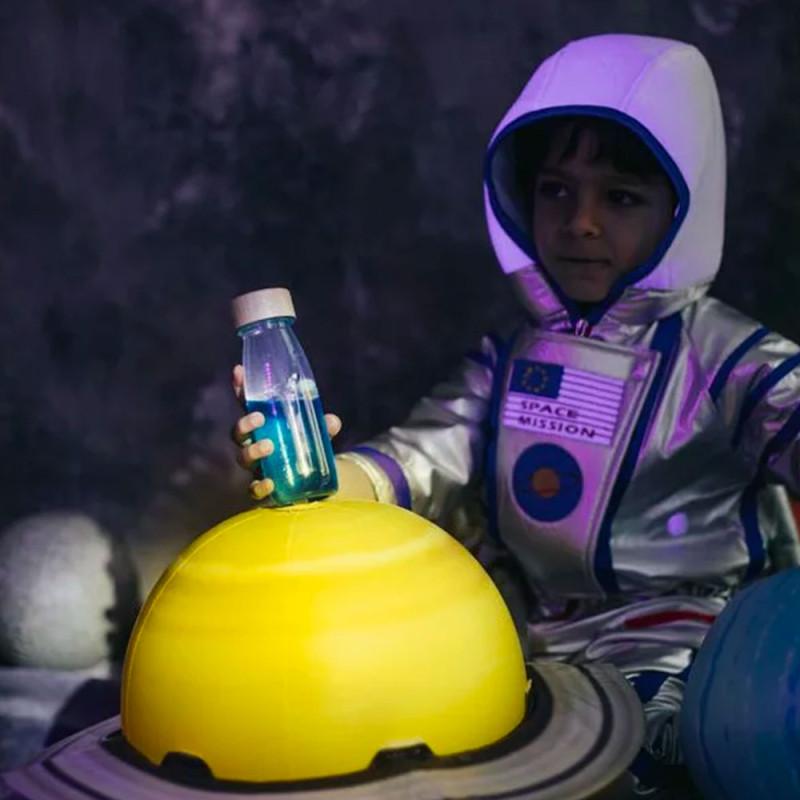 Garçon déguisé en astronaute qui joue avec bouteille univers
