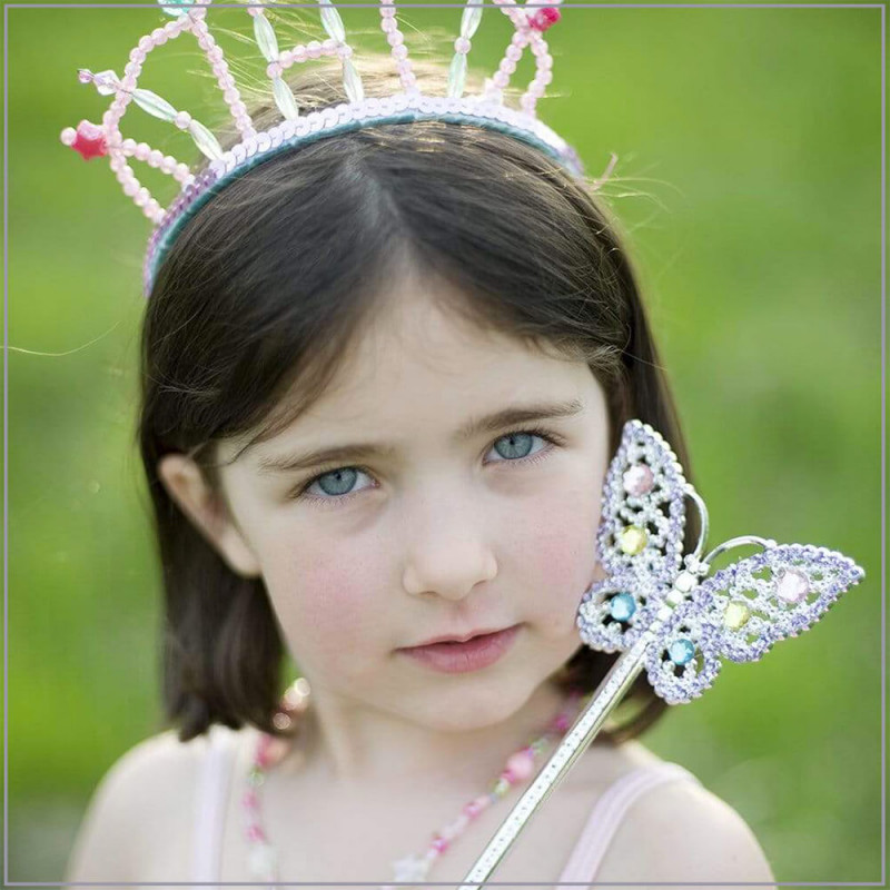 Petite fille déguisée avec baguette à paillettes papillon.