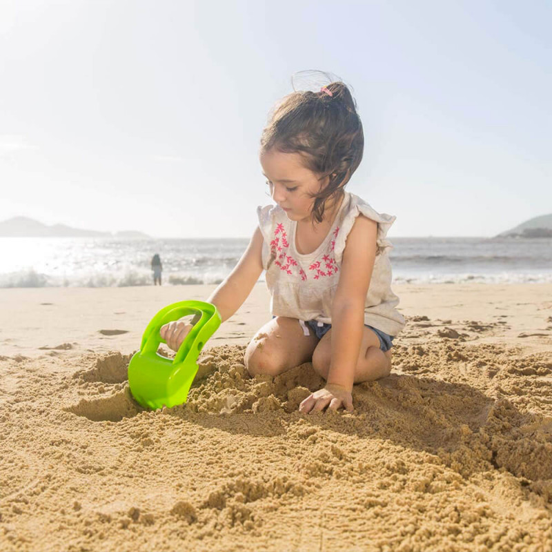 Petite fille avec le jouet de plage Excavatrice verte.