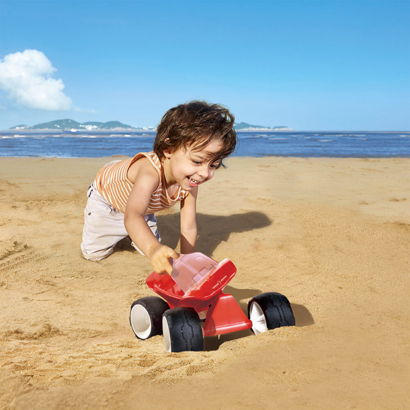 Enfant qui pousse le buggy rouge de Hape à la plage