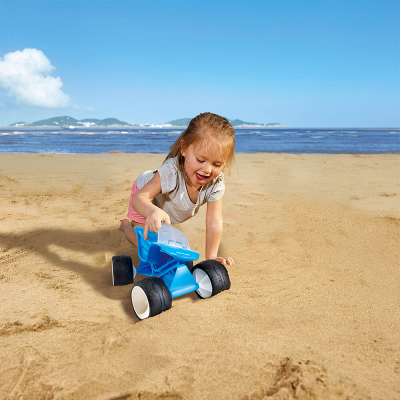 petite fille qui pousse le buggy bleu de Hape à la plage