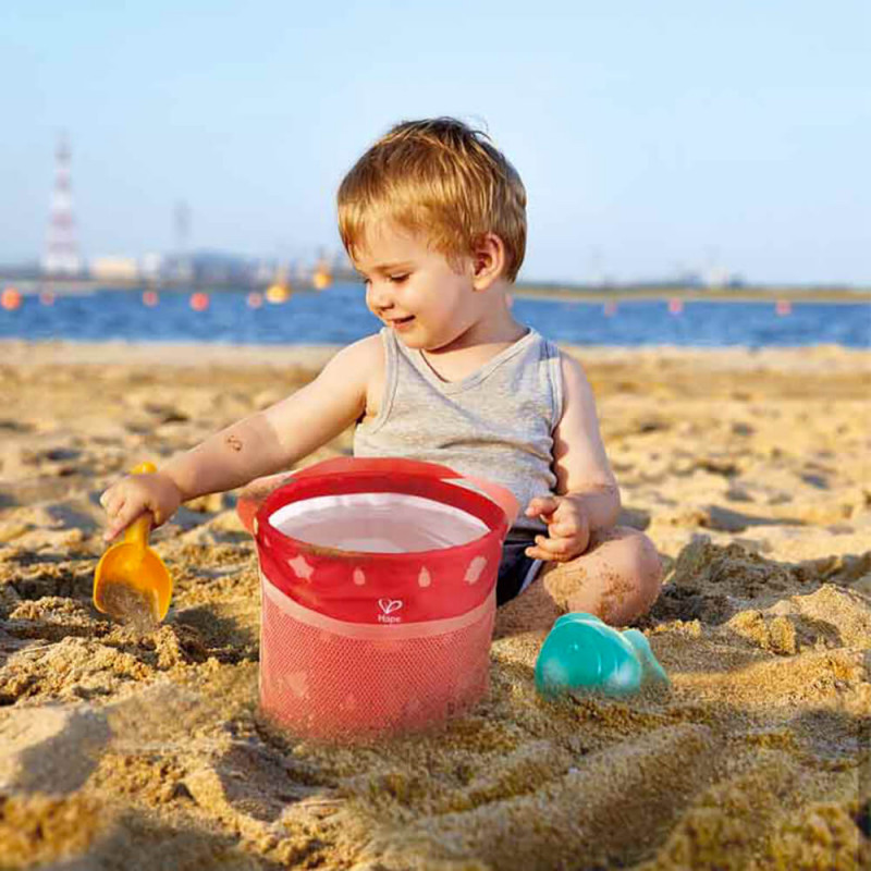 Enfant qui joue dans le sable avec les jouets de plage Hape